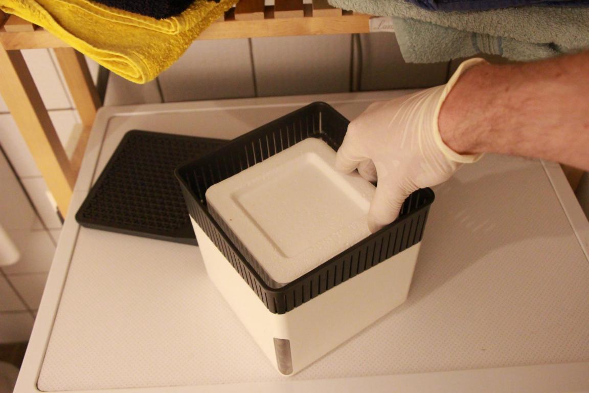 Der Luftentfeuchter ohne Strom steht offen und im Inneren liegt der Granulat-Block, bestehend aus Calciumchlorid.